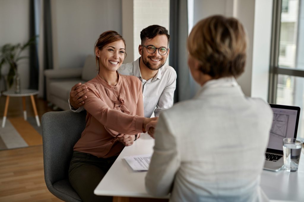 young happy couple shaking hands with insurance agent meeting office scaled 1